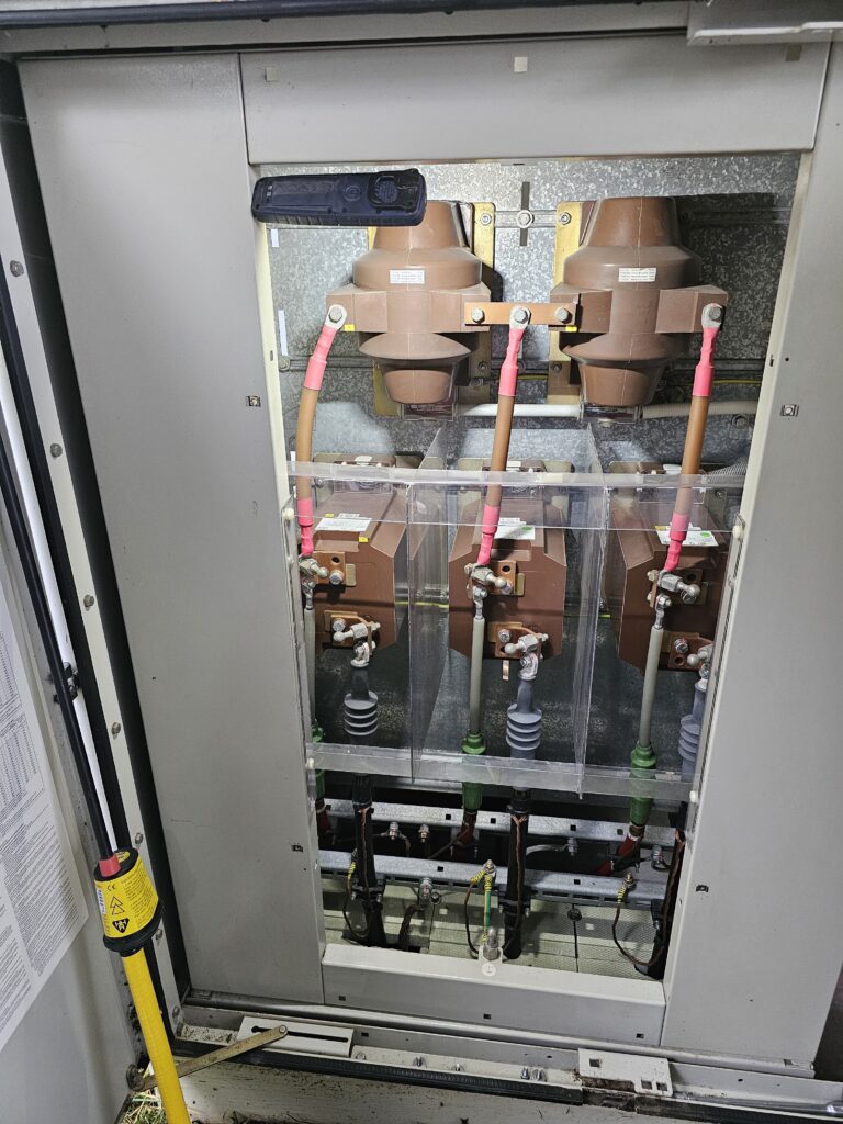 Geöffnete Mittelspannungs‑Schaltanlage mit drei Lasttrennschaltern und braunen Isolierkörpern.