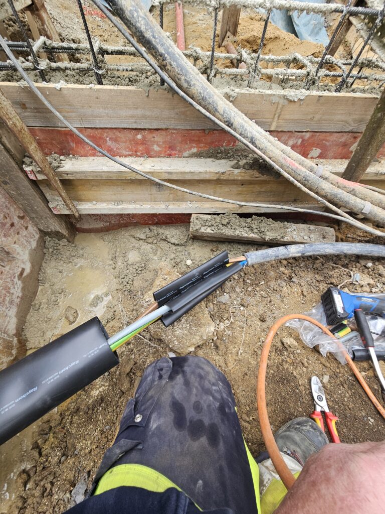 Elektriker installiert Stromkabel mit Schrumpfmuffe auf Baustelle.