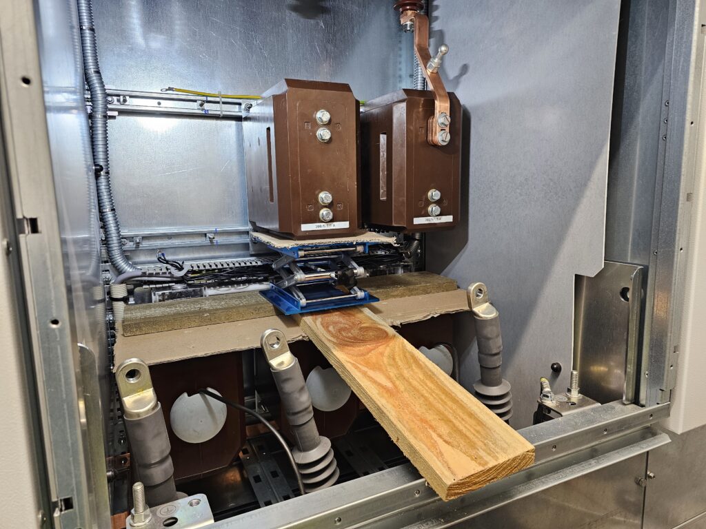 Zwei braune Wandler in Mittelspannungsschrank mit Kupferleitung und Holzplatte zur Montagehilfe.